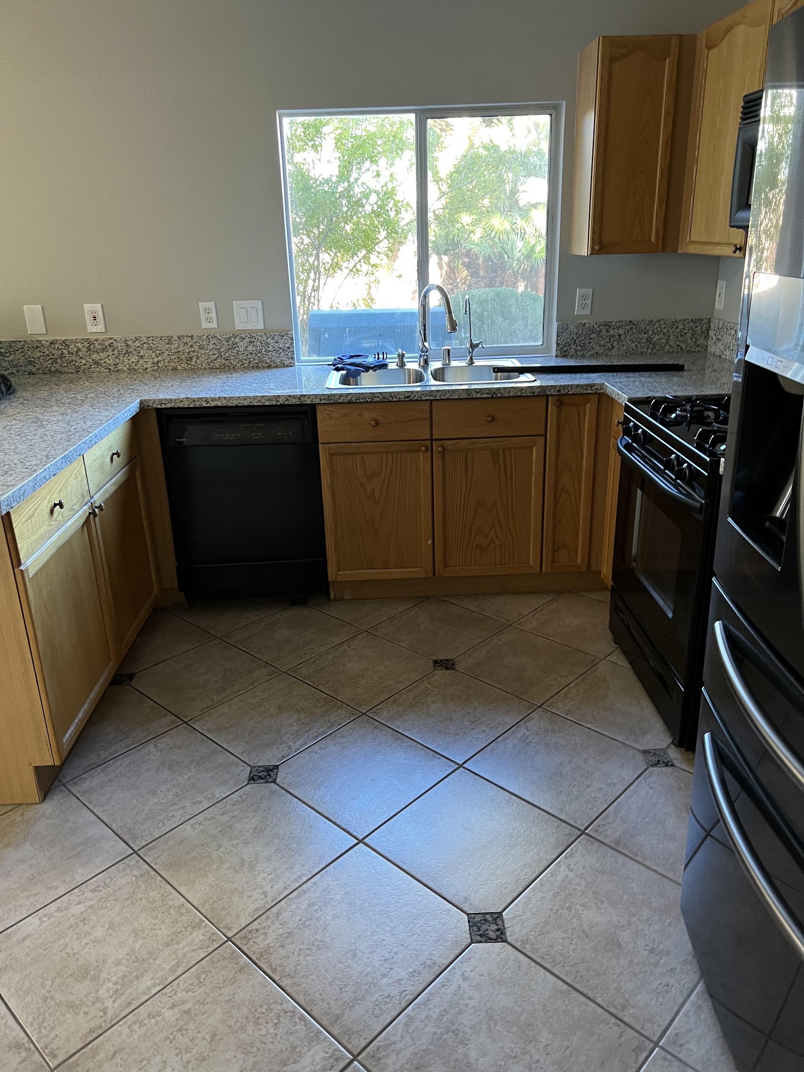 Clean kitchen with tile floor, wood cabinets, and black appliances