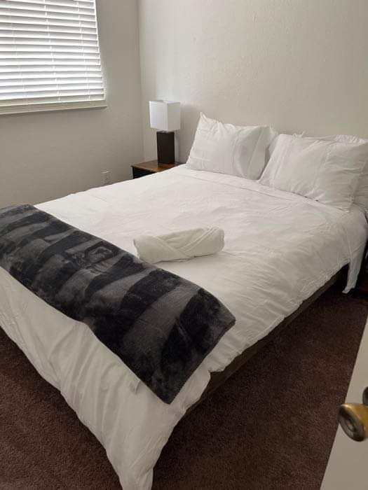 Neatly made bed with white bedding and a folded towel